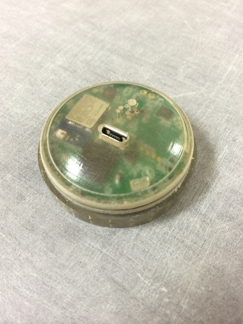 A transparent, 3D-printed circular housing reveals the circuit board and its USB connector.
